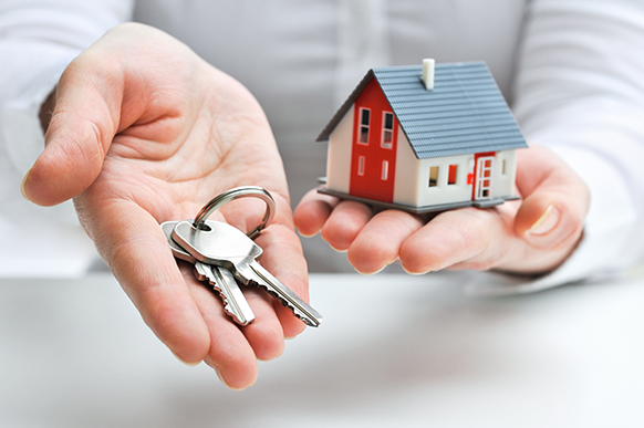 hands holding keys and a small model house